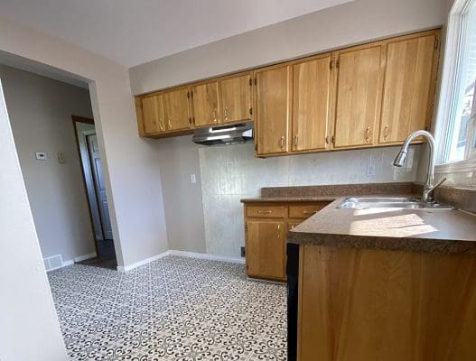 A kitchen with wooden cabinets and tiled floors.