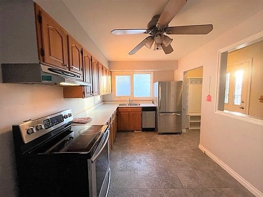 A kitchen with a stove and a ceiling fan.