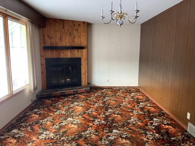 An empty living room with a fireplace and floral carpet.