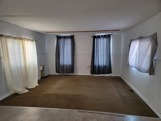 Empty living room with carpet and curtains.