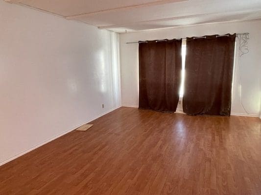 An empty room with wood floors and a window.