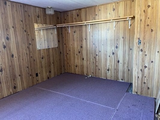 An empty room with wood paneling and a purple carpet.