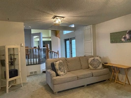 A living room with a couch and a staircase.
