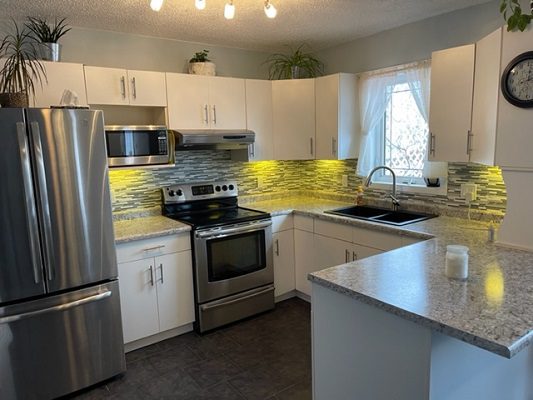 A kitchen with stainless steel appliances and white cabinets.