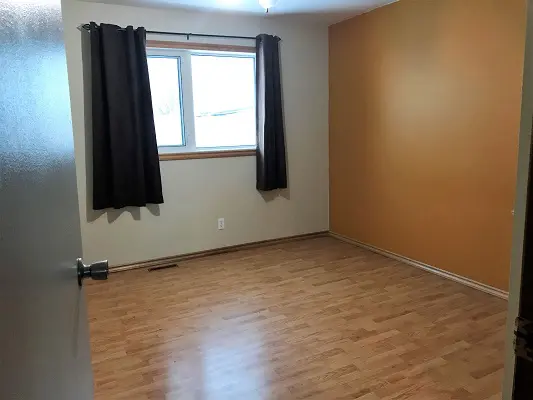 An empty room with orange walls and hardwood floors.