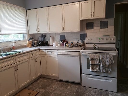 A kitchen with white cabinets and a stove.