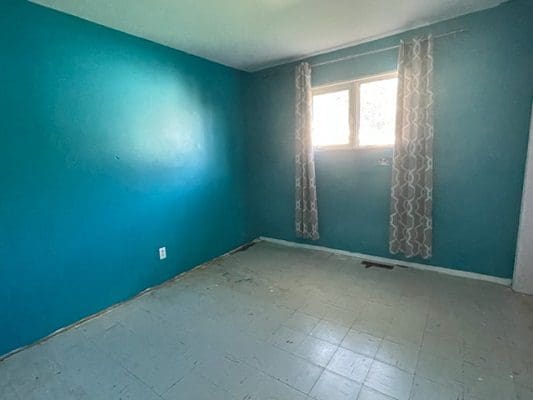 An empty room with blue walls and a window.