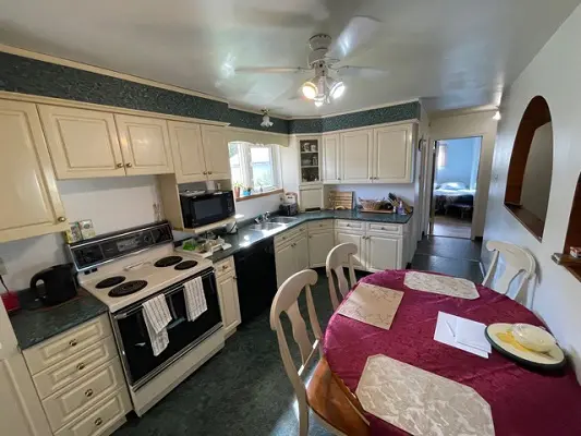 A kitchen with a table and chairs and a ceiling fan.