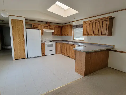 An empty kitchen with wood cabinets and a skylight.
