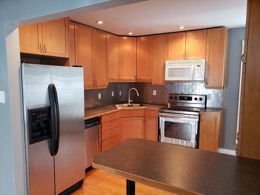A kitchen with stainless steel appliances and wooden cabinets.