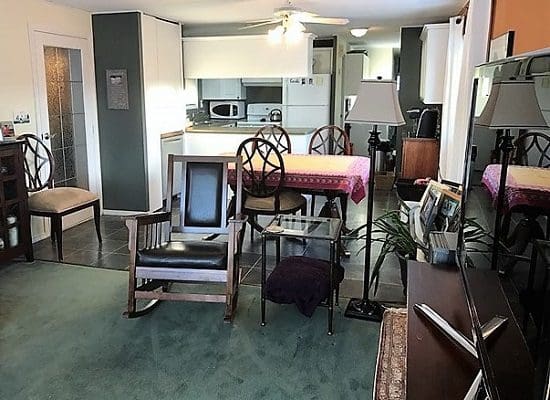 A living room with a rocking chair and a dining table.