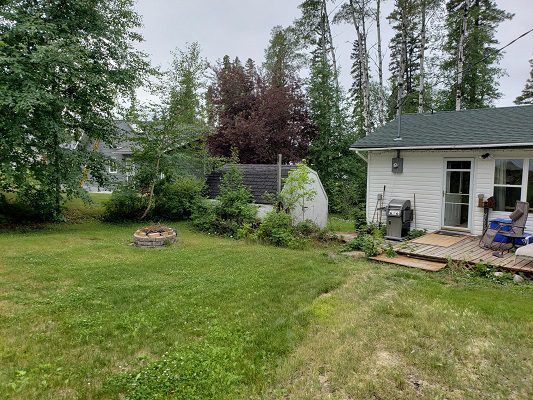 A small backyard with a fire pit and trees.