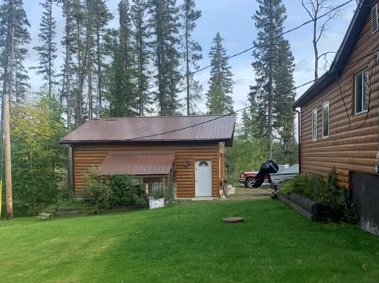 A log cabin with a car parked in front of it.