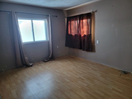 An empty room with wood floors and a window.