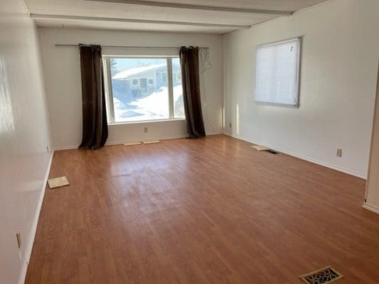 A living room with hardwood floors and a window.