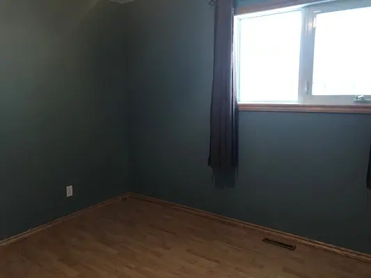 An empty room with blue walls and a window.