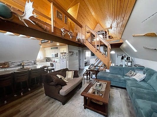 A living room in a log cabin with a loft.
