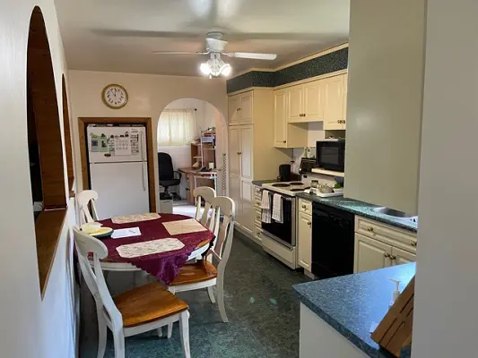 A kitchen with a table and chairs and a ceiling fan.