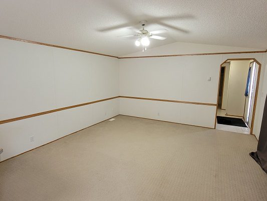 An empty room with white walls and a ceiling fan.