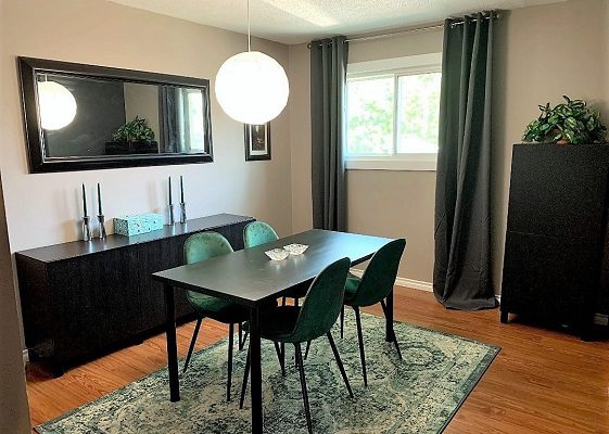 A dining room with green chairs and a mirror.