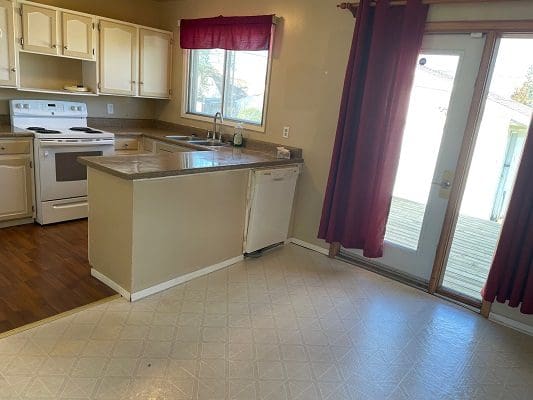 A kitchen with white cabinets and wooden floors.