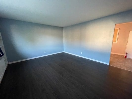 An empty room with blue walls and hardwood floors.