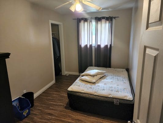 A small bedroom with a bed and a fan.