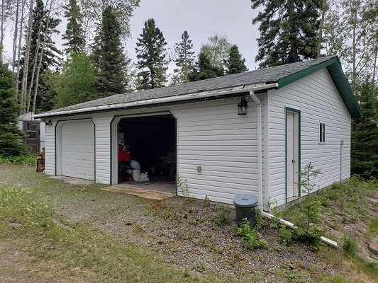 A garage in a wooded area with trees in the background.