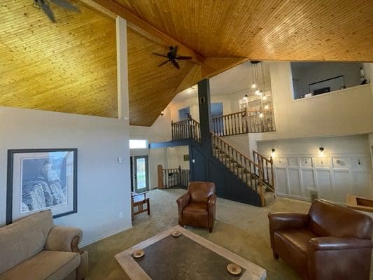 A living room with wood ceilings and couches.