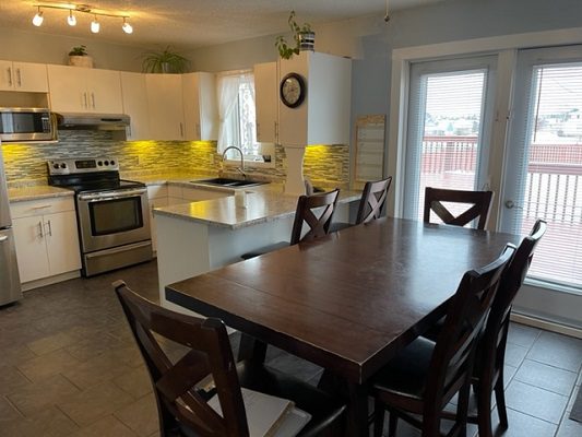 A kitchen with a table and chairs and a refrigerator.