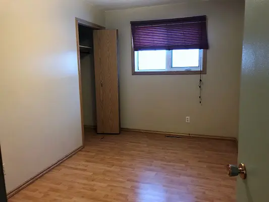 An empty room with hardwood floors and a closet.