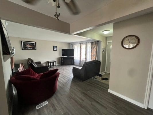 A living room with hardwood floors and a ceiling fan.