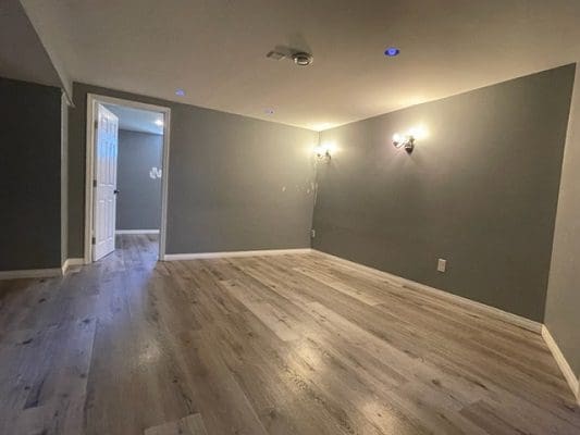 An empty room with gray walls and hardwood floors.