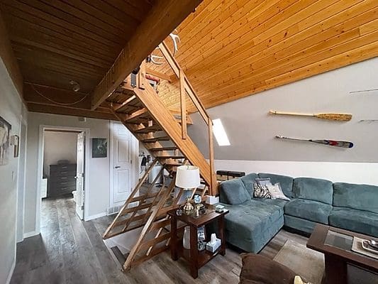 A living room with a wooden staircase and a couch.