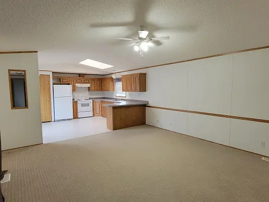 An empty kitchen with white cabinets and a ceiling fan.