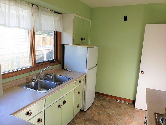 A kitchen with green walls and a white sink.