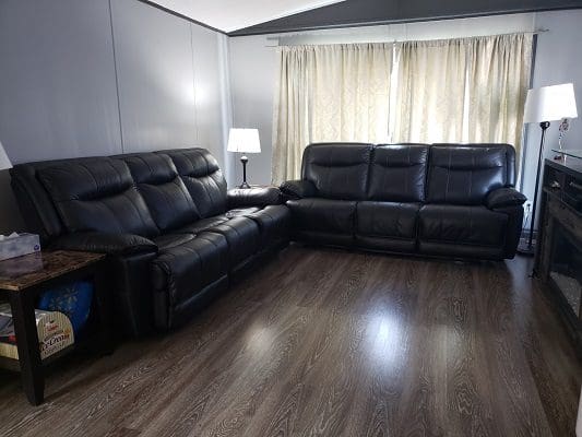 A living room with black leather furniture and a fireplace.