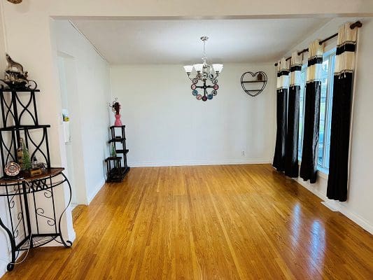 An empty living room with hardwood floors and a chandelier.