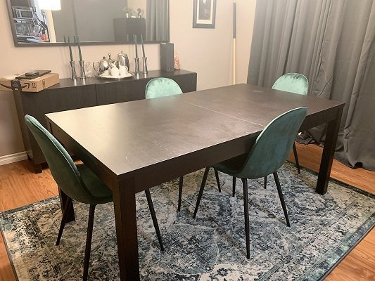 A dining table with four chairs and a rug.