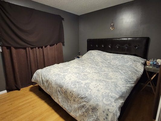 A bedroom with black walls and a white bed.