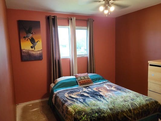 A bedroom with orange walls and a painting on the wall.