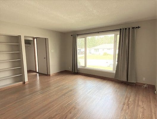An empty room with hardwood floors and a window.