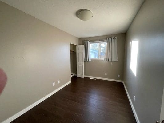 An empty room with hardwood floors and a window.