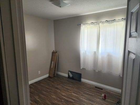 An empty room with hardwood floors and a window.