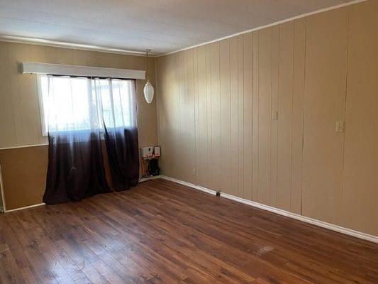 An empty room with wood floors and a window.