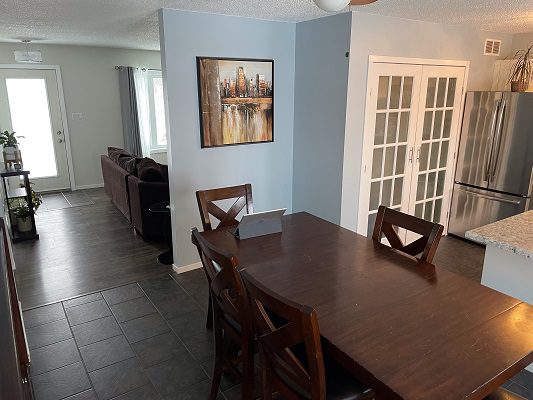 A kitchen with a table and chairs and a refrigerator.