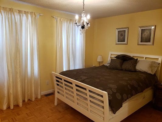 A bedroom with yellow walls and a bed.