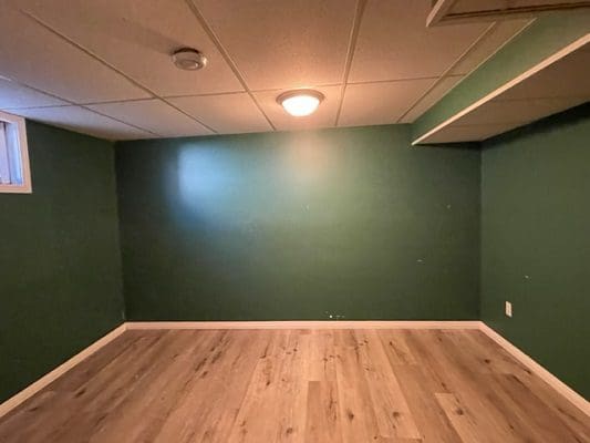 An empty room with green walls and hardwood floors.