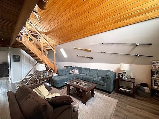 A living room with a wooden ceiling and stairs.
