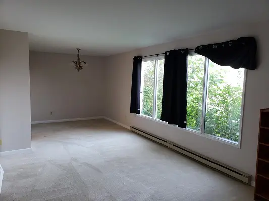 An empty living room with a large window.